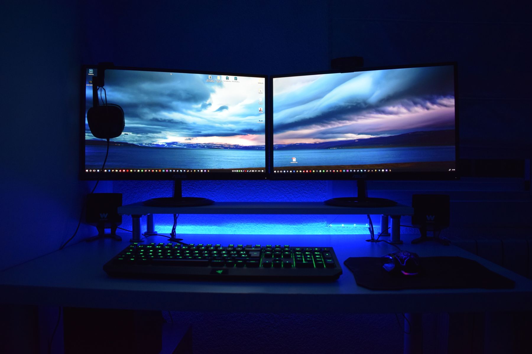 Two monitors, a backlit keyboard, and a mouse on a white desk.